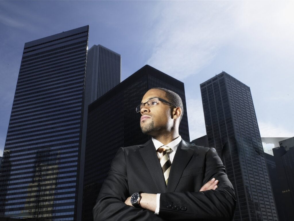 Business professional in suit with city skyline background at sunset.